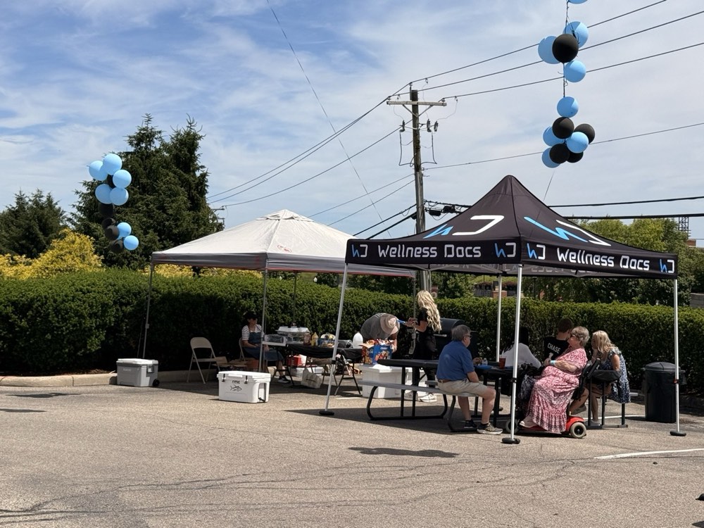 Guests hanging out under the Wellness Docs tents with snacks and drinks